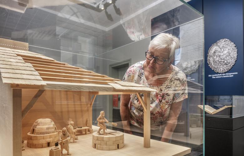 ältere Dame schaut sich ein Hütten-Modell an